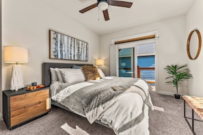 A bedroom with a bed, bedside tables, a ceiling fan, a window with a view, and a potted plant. - Westwoods 4BR Mountain Home | Sauna + Shuffleboard | Sleeps 8 | Pet OK (Leadville)