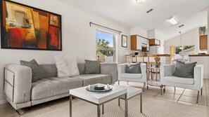 Relax in this stylish living space with a sofa, coffee table, and dining area, offering a view of the outdoors.