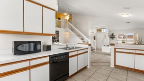 Enjoy cooking in this well-equipped kitchen with a central island, appliances, and a staircase leading to the upper level.