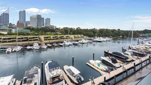 A marina with boats docked, a city skyline in the background, and a clear sky. - Loft-Style Waterfront Apartment (Woolloomooloo)