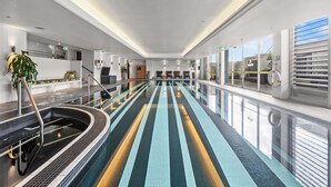 A modern indoor swimming pool with a long, straight layout and a tiled floor. - Loft-Style Waterfront Apartment (Woolloomooloo)
