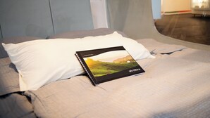 A bed with a white pillow and a book titled 'Gastebluch' on it. - Eine Nacht im Museum - LUNA Sleep Cube (Lueneburg)