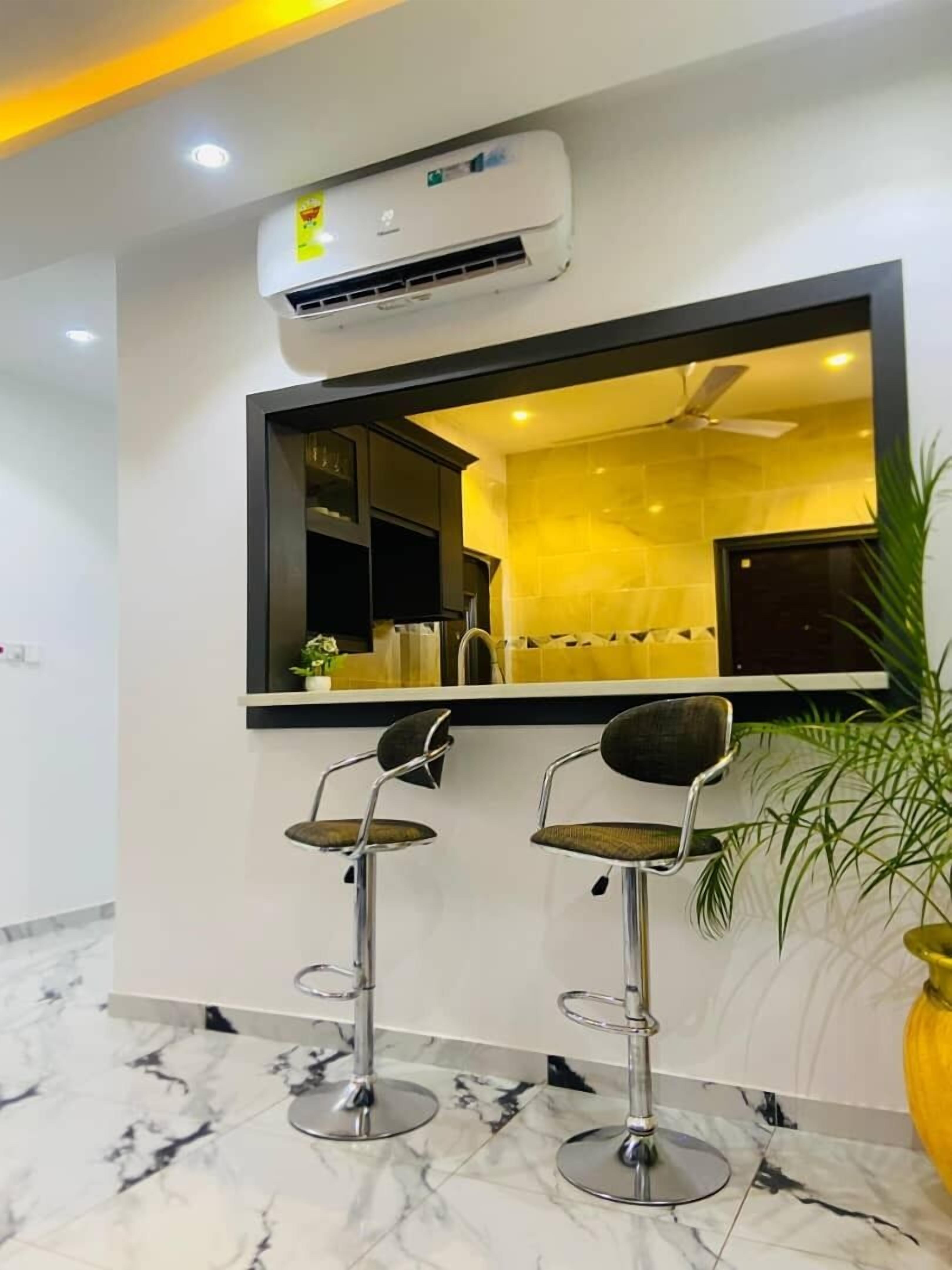 Un baño moderno con un espejo grande, dos taburetes, un ventilador de techo y un equipo de aire acondicionado.