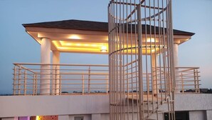A multi-level building with a covered outdoor area, a staircase, and a railing. - Jac-Kuw Splendour Homes (Accra)