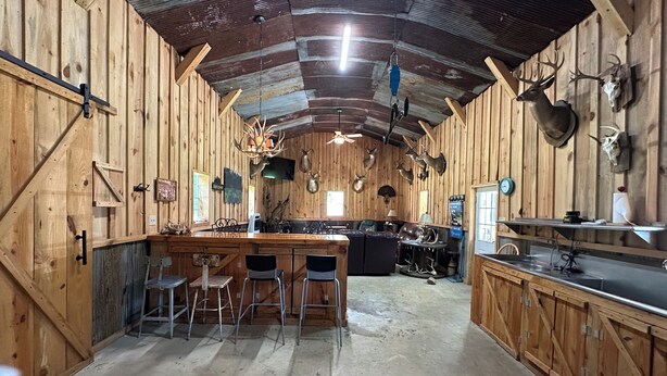 A rustic wooden interior with a bar area, seating, and mounted animal heads on the walls. - Charming 3-bedroom cabin in Autaugaville with AC and Hangout Building (Autaugaville)