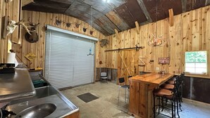 A rustic kitchen with a wooden counter, a sink, and a bar area with stools. - Charming 3-bedroom cabin in Autaugaville with AC and Hangout Building (Autaugaville)