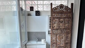 A compact kitchen with a white countertop, a sink, and a window. A decorative wooden panel is visible in the doorway. - TOWNHOUSE 5 MN WALK FROM CANNES CROISETTE (Cannes)
