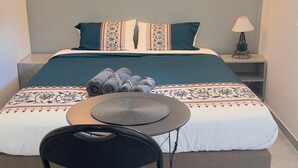 A neatly arranged hotel room with a bed, a small round table, a chair, and two wall-mounted lamps. - TOWNHOUSE 5 MN WALK FROM CANNES CROISETTE (Cannes)