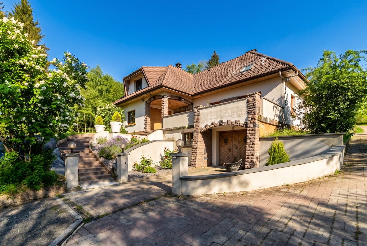 Une maison à deux étages avec une façade en briques, une entrée principale dotée d’une porte en bois et un escalier menant à l’étage supérieur.