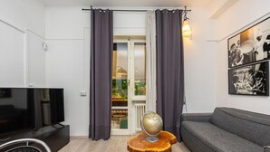 A modern living room with a flat-screen TV, a sofa, a round wooden table with a globe, and a large window with curtains. - Loquat House by Rentbeat (Roma)