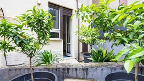 A courtyard with potted plants, a stone bench, and a building entrance. - Loquat House by Rentbeat (Roma)