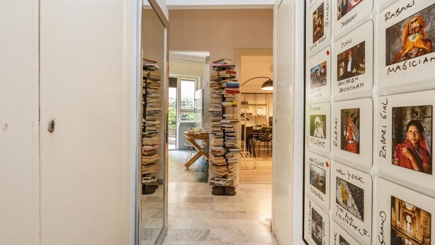 A hallway with a bookshelf, a dining area, and a wall with framed pictures. - Loquat House by Rentbeat (Roma)