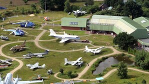 Vista aérea de una pista de vuelo con varios aviones y un gran hangar.