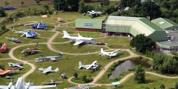 An aerial view of an airfield with various aircraft and a large hangar.
