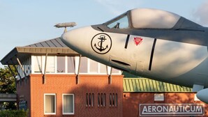 Un avión con un logotipo y el texto "AERONAUTICUM" en un edificio al fondo.