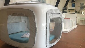 Una cápsula de descanso moderna y compacta con ventana transparente, una almohada y un panel de control.