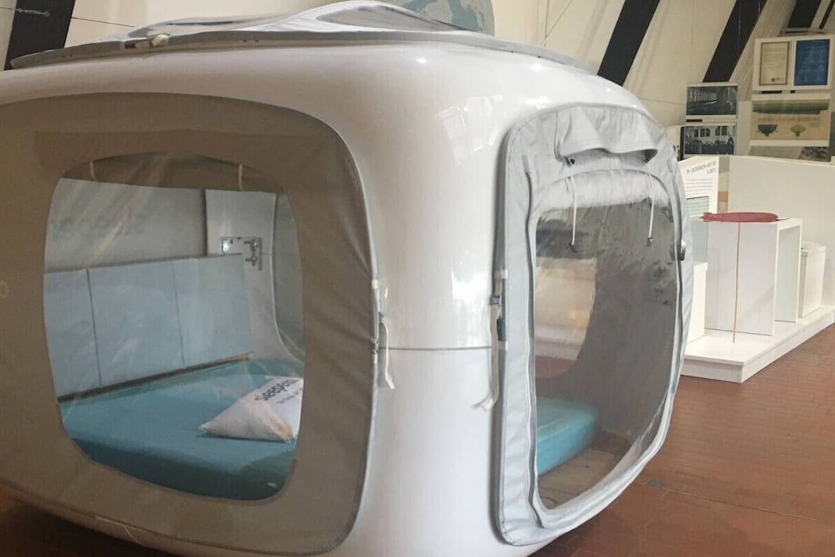Una cápsula de descanso moderna y compacta con ventana transparente, una almohada y un panel de control.