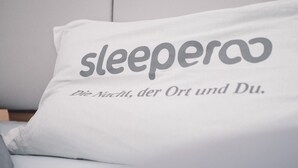 Un almohadón con el texto "sleepero" y "Die Nacht, der Ort und Du".