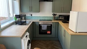 Eine kompakte Küche mit Waschmaschine, Esstisch und eingebautem Backofen.