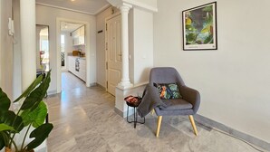A hallway with a modern chair, a large plant, and a framed picture on the wall. - Aloha Banús Sea Views by Lica Homes (Marbella)