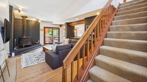 Un vaste espace de vie doté d’une cheminée, d’un escalier et offrant une vue sur l’extérieur.