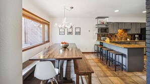 Une cuisine moderne avec un îlot central en bois, des tabourets de bar et un lustre.