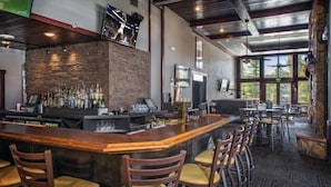 A bar area with a stone wall, bar stools, and a television mounted above the bar.