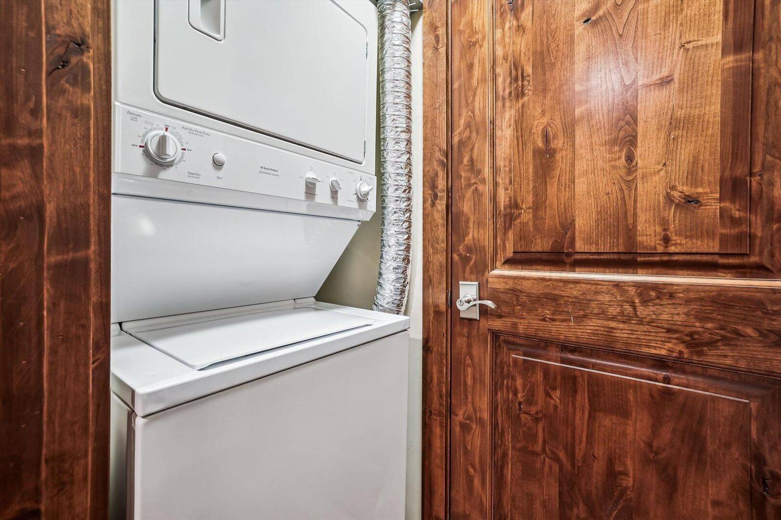 A white washing machine in a wooden utility room with a door.