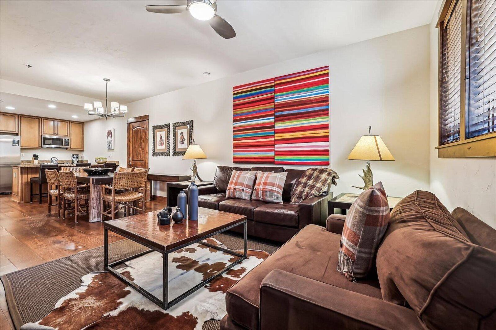 A spacious living room with a large sofa, a coffee table, and a dining area with chairs and a table.