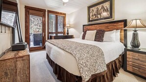Une chambre avec un grand lit, un ventilateur de plafond, un tableau et une cheminée.