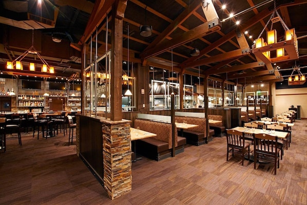 A restaurant with wooden beams, stone pillars, and multiple seating areas including booths and tables.