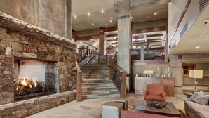 A spacious lobby with a stone fireplace, a staircase, and a seating area with a coffee table. - Ski-in/ski-out One Ski Hill Place 2 Bedroom Luxury Condo (Breckenridge)