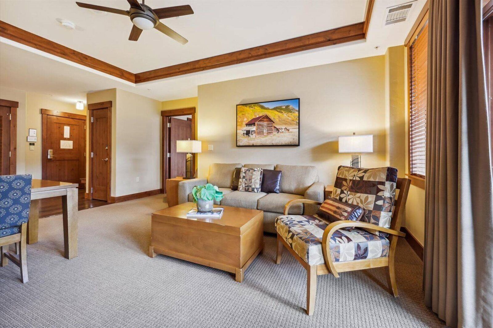 A spacious living room with a wooden ceiling, a sofa set, a coffee table, and a painting on the wall.