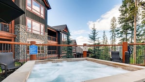 A hot tub area with a stone border, wooden deck, and a sign indicating it is a pool and spa area. - Bluesky Breckenridge Luxury 3 Bedroom Condo at Snowflake Lift (Breckenridge)