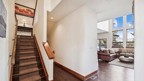 Un vaste espace de vie agrémenté d’un escalier en bois, d’une grande fenêtre offrant une vue agréable et d’un coin salon confortable.