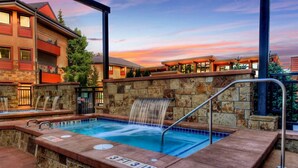 A hot tub with a waterfall feature, surrounded by stone walls and a pool. - Ski-in/ski-out 2 Bedroom Condo at The Village at Breckenridge (Breckenridge)