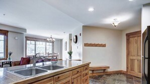Una cocina con una isla grande, armarios de madera, un lavabo y una zona de comedor con sillas y una mesa.