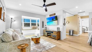 Un salon moderne avec un canapé, une table basse, un téléviseur et un ventilateur de plafond.
