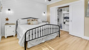 Une chambre à coucher comprenant un lit, une table de chevet, une armoire et un ventilateur de plafond.