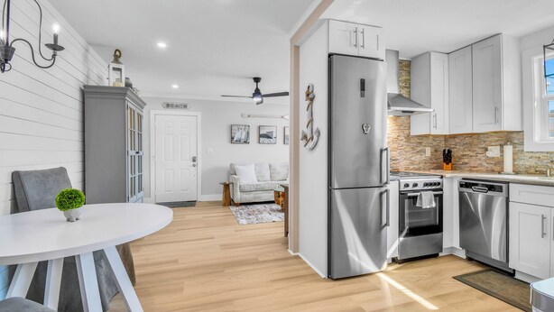Une cuisine moderne dotée d’appareils électroménagers en acier inoxydable, un coin repas avec une table ronde et un espace salon confortable agrémenté d’un tapis à motifs.