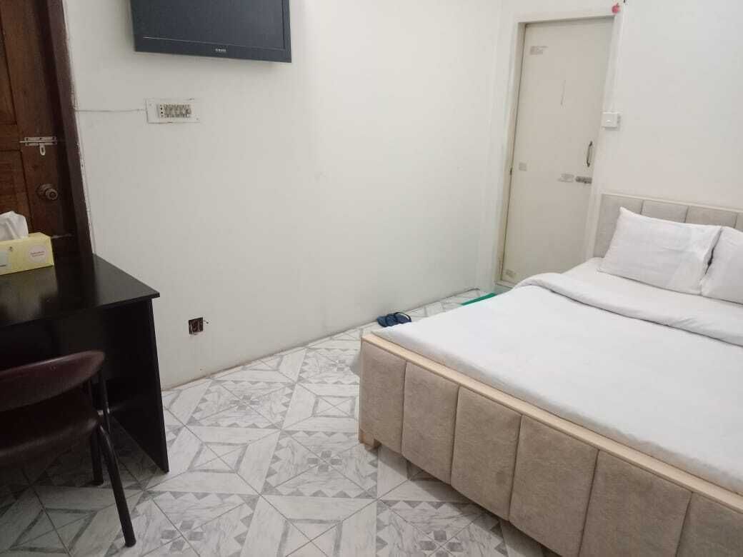 A bedroom with a bed, a desk, and a chair.
