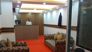 A reception area with a wooden reception desk, two patterned sofas, and a red carpet. - HOTEL GOLDEN BIRD (Dhaka)