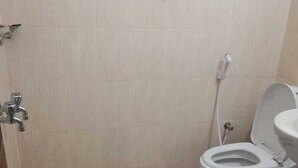 A small, clean bathroom with a toilet, a sink, and a shower. - HOTEL GOLDEN BIRD (Dhaka)