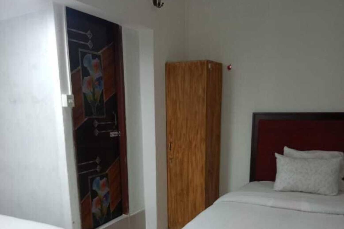 A hotel room with a bed, a wardrobe, and a door with a colorful mural.