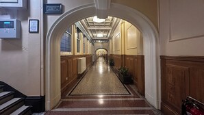 Pasillo de hotel con una pasarela central, paneles de madera y un cartel que indica la ubicación de la escalera.