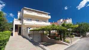 Un edificio residencial de varios pisos con un camino pavimentado y un espacio exterior cubierto con plantas.