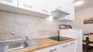Cocina moderna con armarios blancos, un lavamanos de acero inoxidable, encimera de madera y un tostador empotrado.