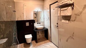 Ein modernes Badezimmer mit Marmorboden, Waschbecken, Toilette und Duschbereich.