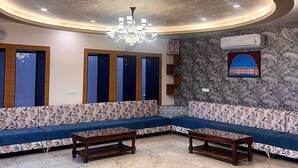 Eine Lobby mit gewölbter Decke, einem Kronleuchter, einem gemusterten Sofa und einer Steinwand mit einem gerahmten Bild.