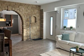 Relax in this inviting living room with a sofa, side table, and plant, surrounded by a stone archway and large window.